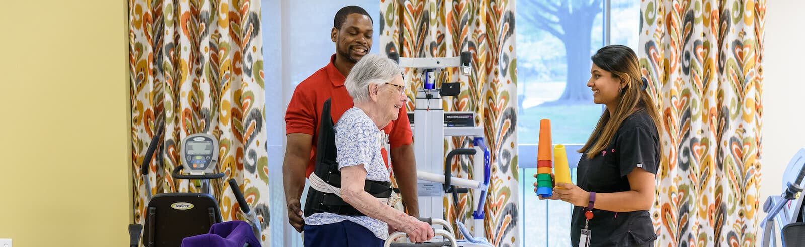 Physical therapists assist senior with walker