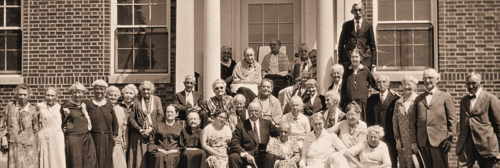 Historical B&W photo of residents gathered on the steps of the Administration Building