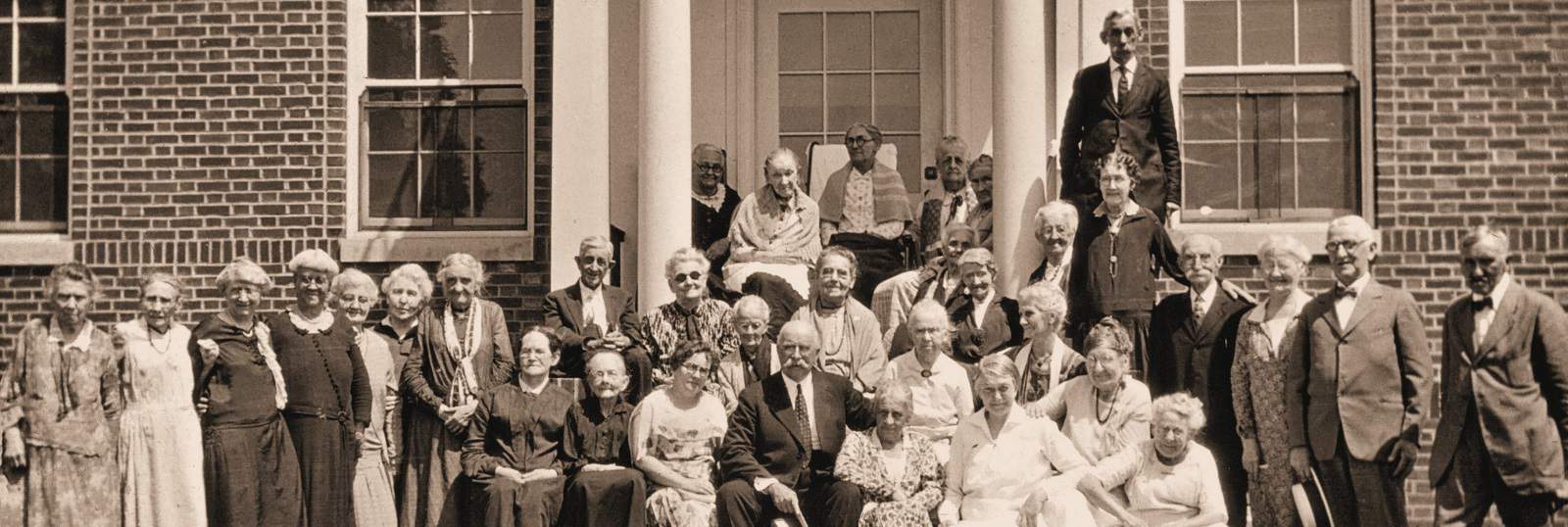 Historical black and white photo of residents gathered on the steps of the Asbury Methodist Village Home for the Aged.