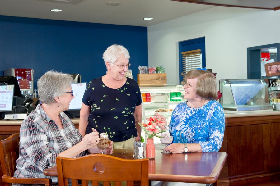 Three senior women talking at the collegiate cafe
