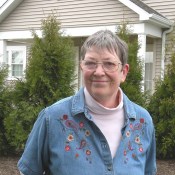 An older woman, Karen Keene in front of her Springhill home and some trees