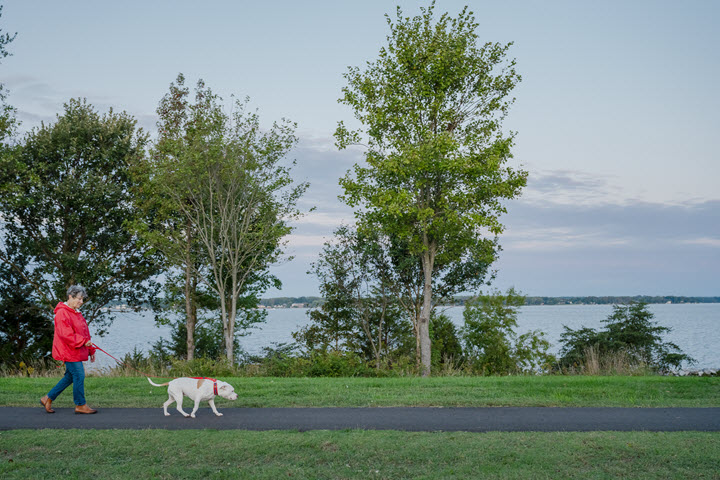 a senior woman walking a dog waterfront