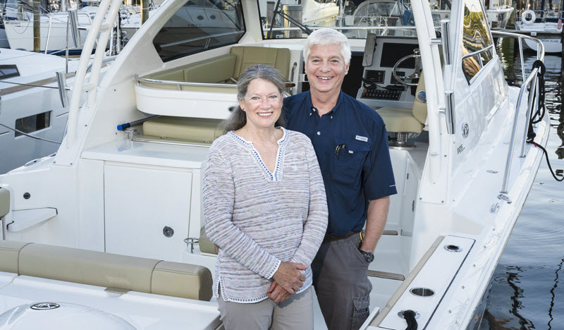 older couple standing on their boat at the marina