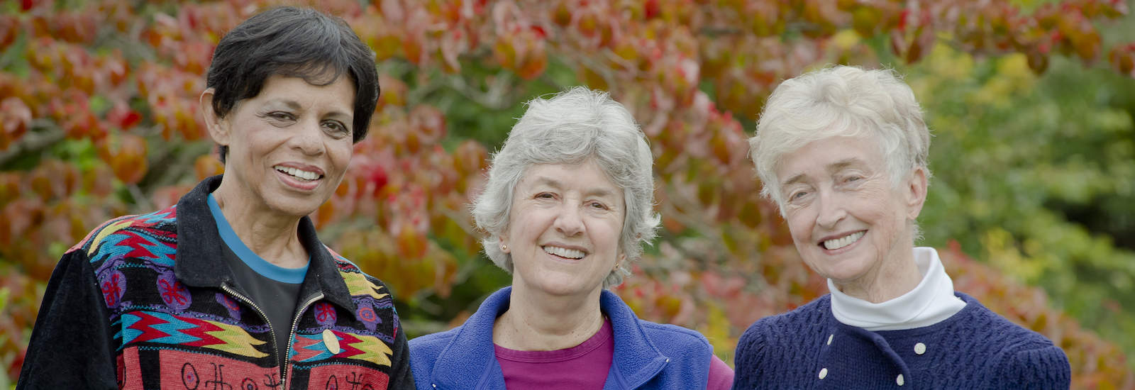 three older woman standing close together and looking at the camera