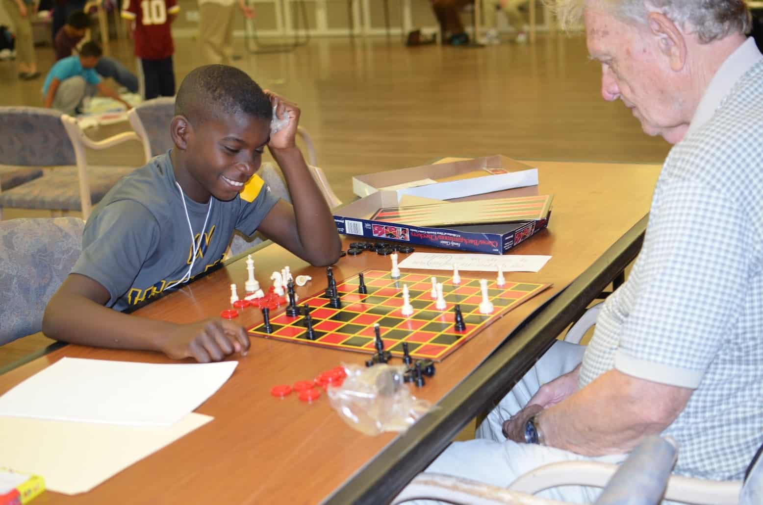 senior playing chess with child