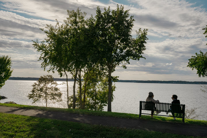two seniors sitting on a bench, waterside