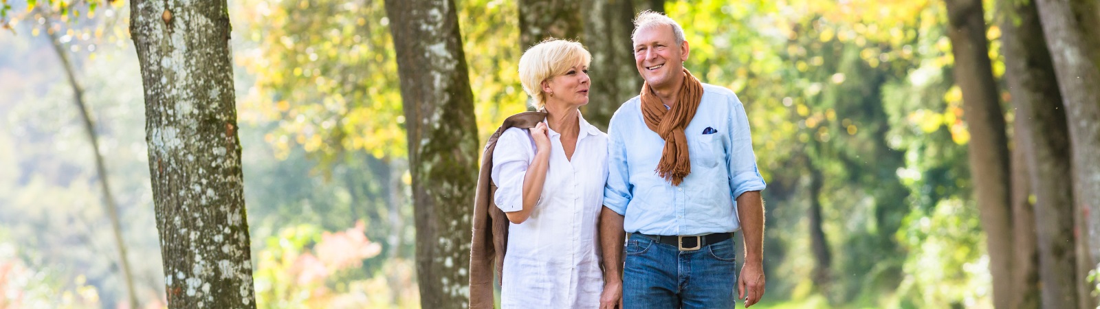 Senior couple walking in the woods in fall.