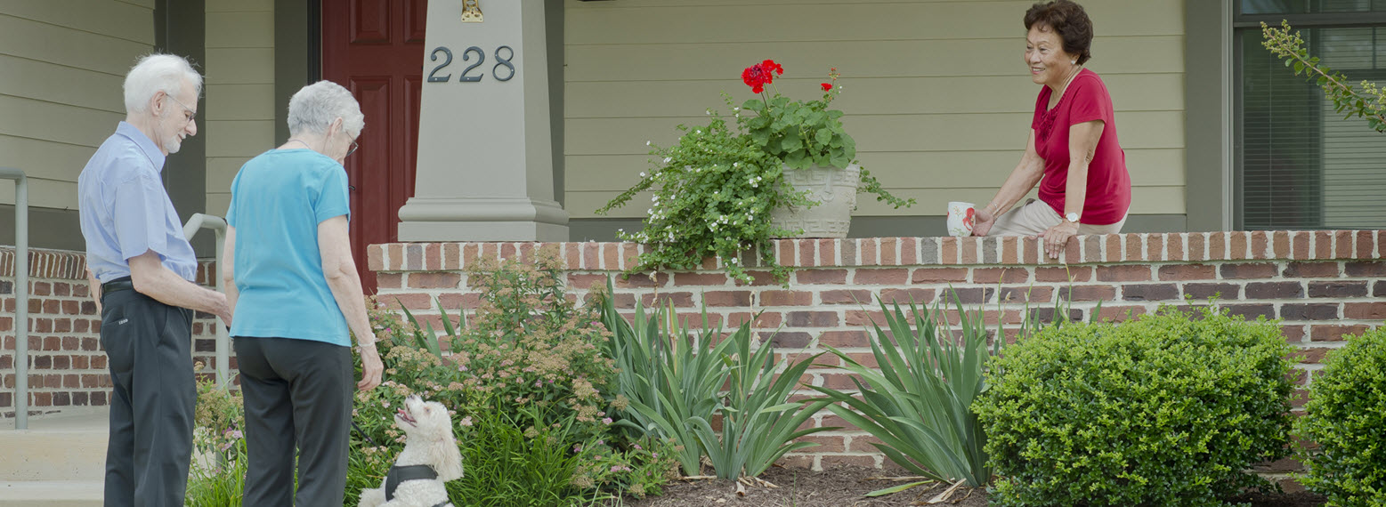 two seniors, a couple, at edge of another seniors porch, dog with the couple