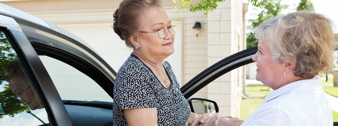 staff member assisting resident out of her car