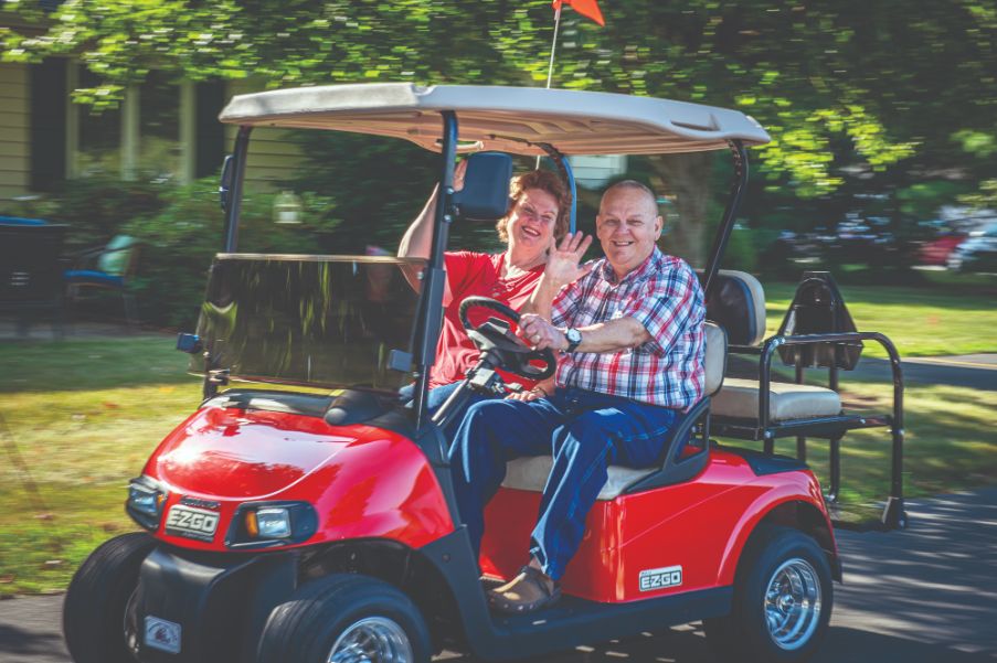 residents driving a golf cart around riverwoods