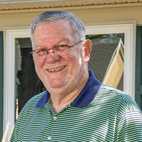 Senior male smiling in front of cottage