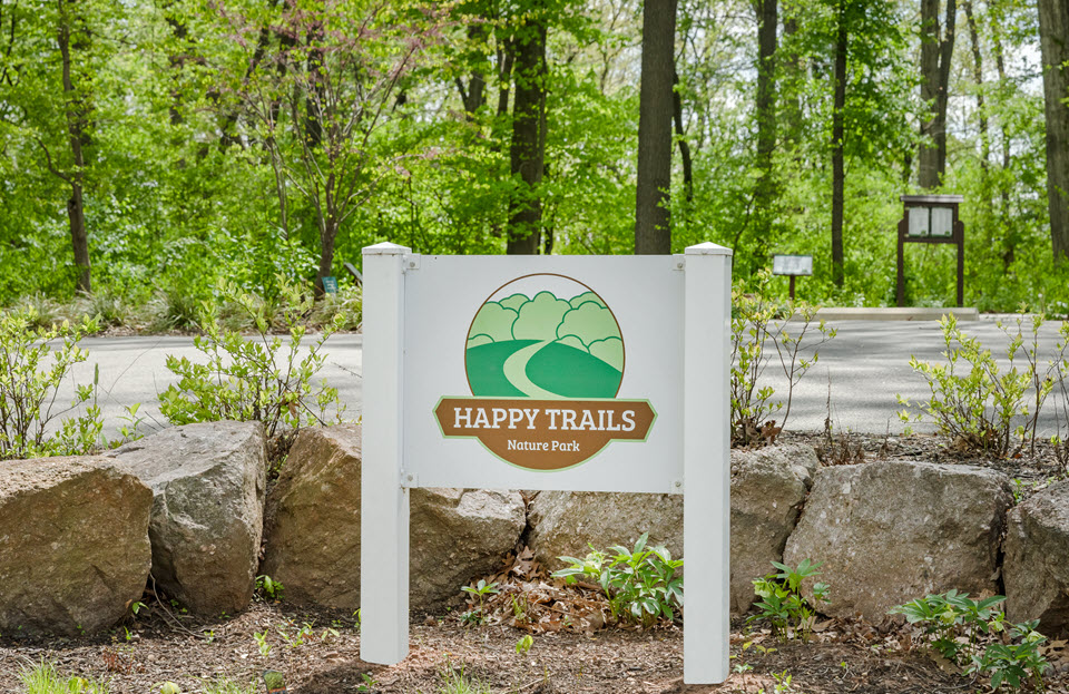 happy trails nature park sign showing name and logo with path
