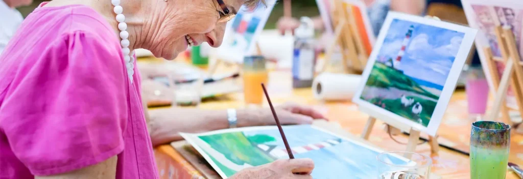 older woman doing watercolor painting at a class outdoors