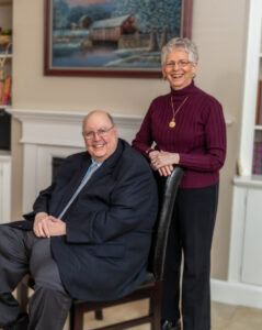 Dean Wilson and wife pose in front of fireplace in Garden Home