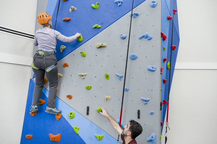 senior woman climbing rock wall at Asbury