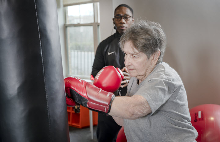 woman hits boxing bag in wellness center