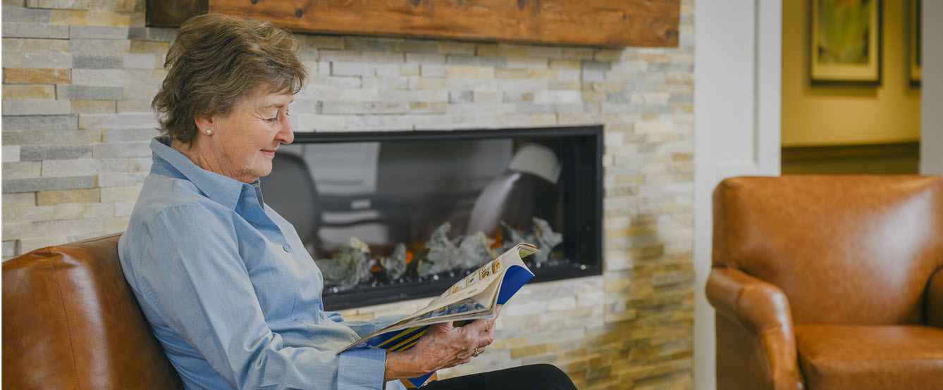 Kayce Dildine reading in front of fireplace alone