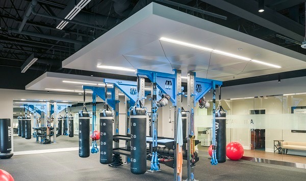 Well lit gym with numerous weights and punching bags and large mirror on the backwall.