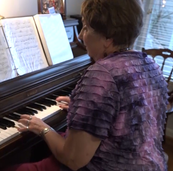 senior woman sits at piano playing a song at Asbury Solomons retirement community