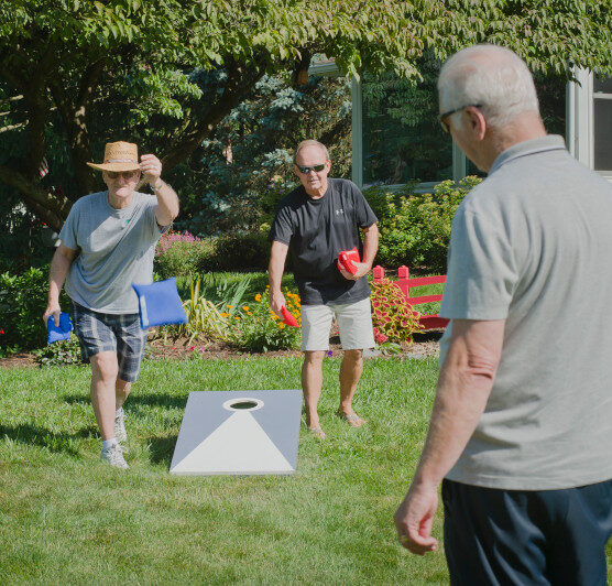 4 men playing cornhole outside