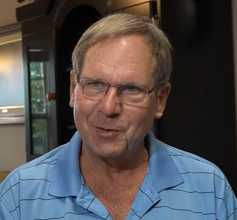 man with glasses looking at camera and talking in his living room