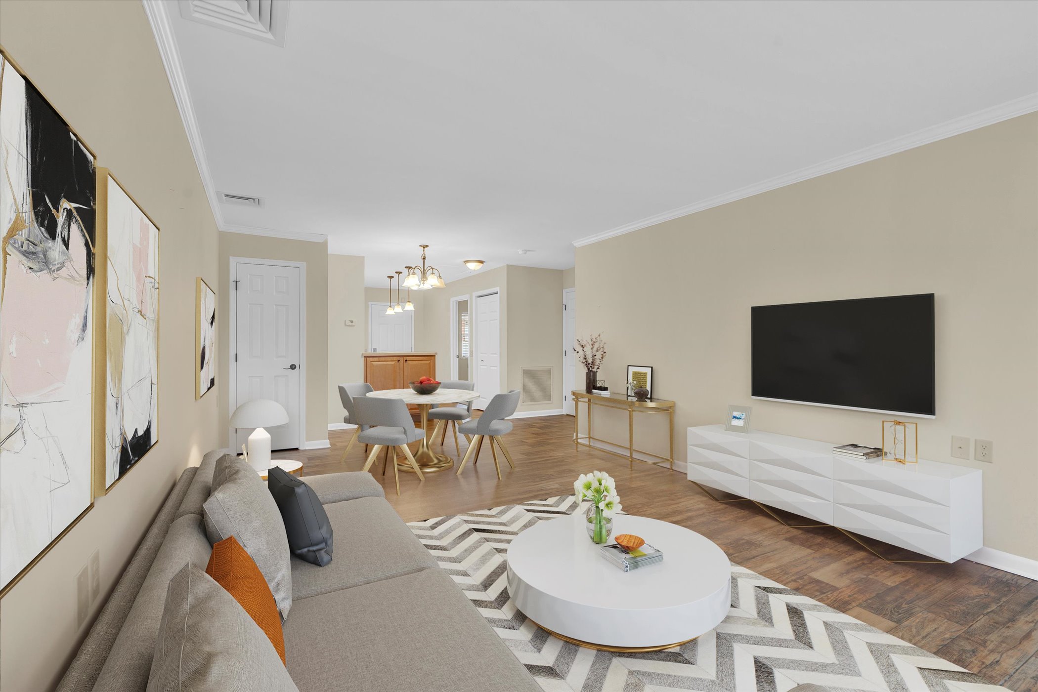 contemporary living room with taupe couch and upholstered coffee table looking into open kitchen and dining area