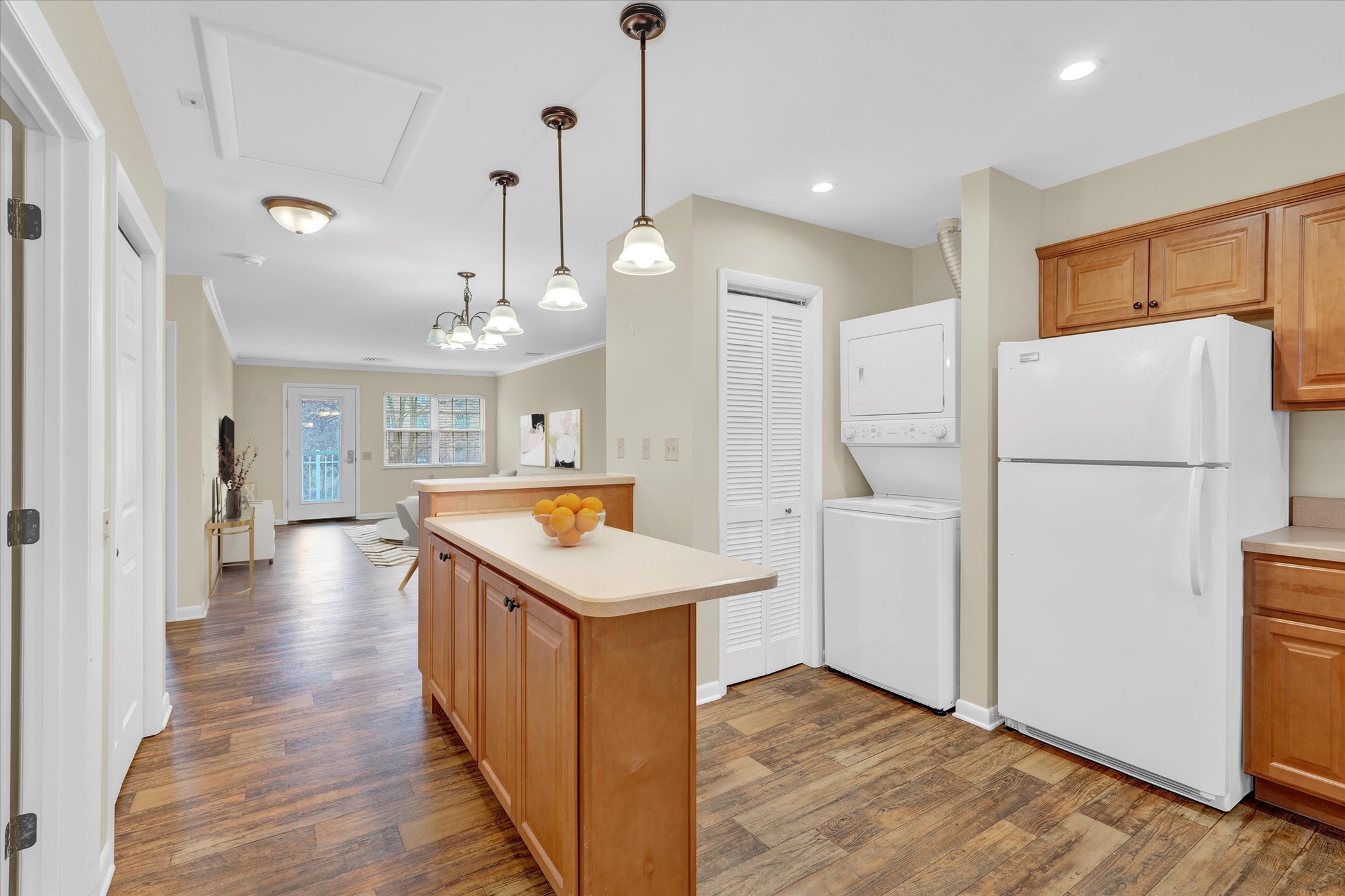 open floor plan kitchen with oak eat-in island and pendant lighting looking into living room with hardwood floors