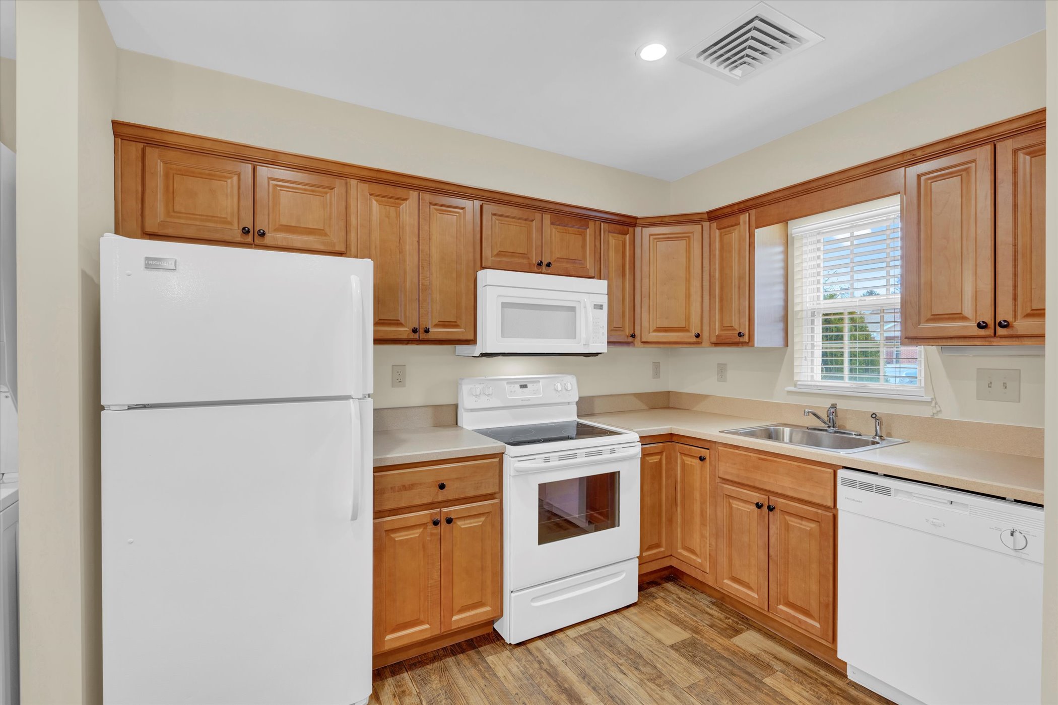 kitchen with light oak cabinets and white appliances with large window above sink