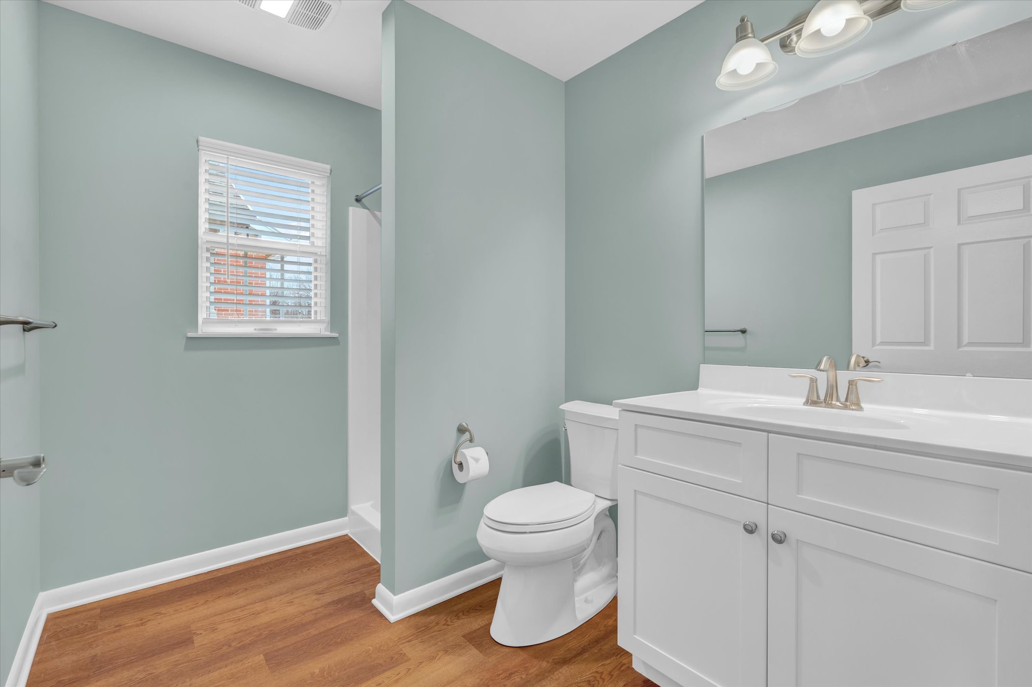 bathroom with white sink, toilet and shower behind wall