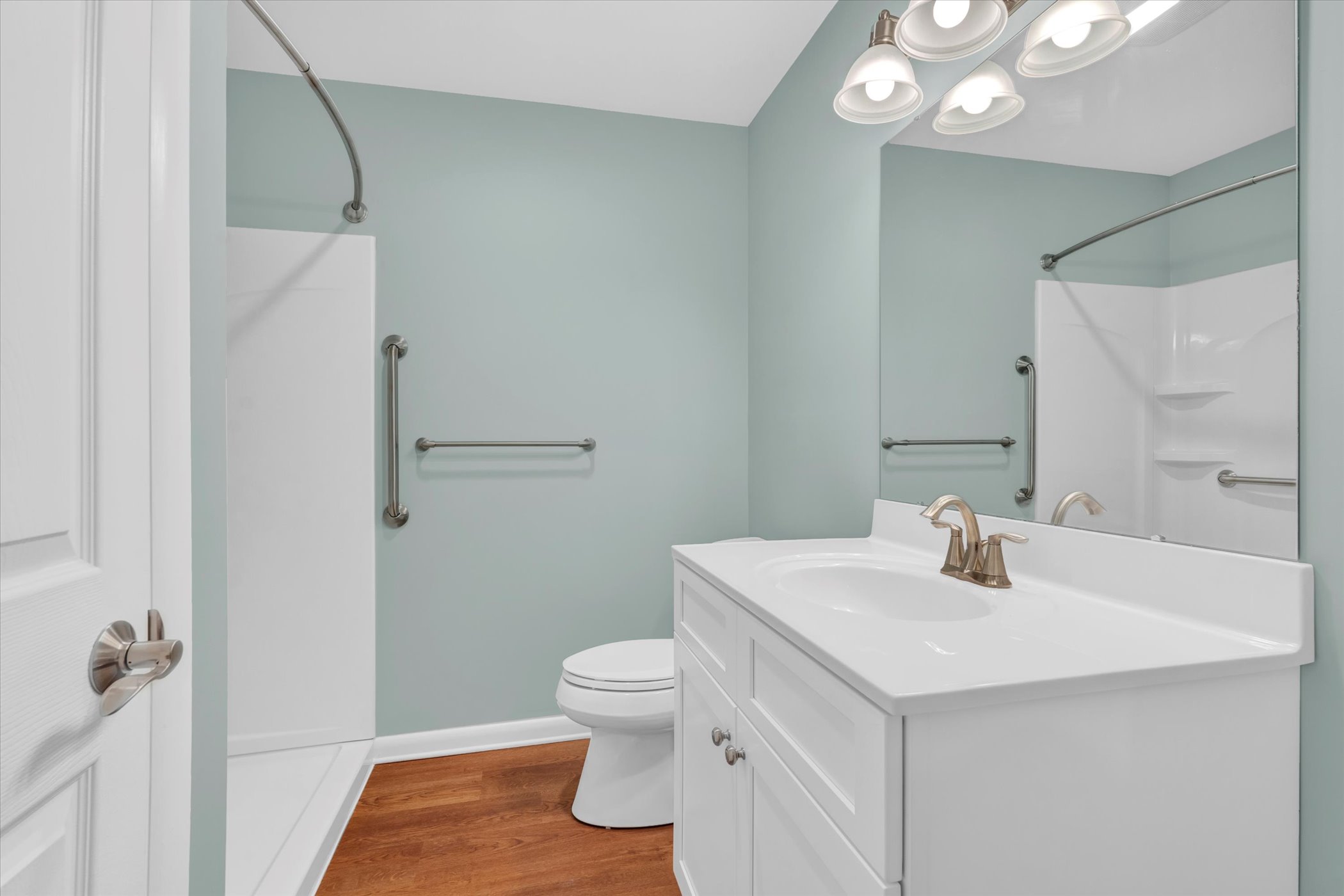 bathroom with pale green walls and white sink cabinet and walk in shower
