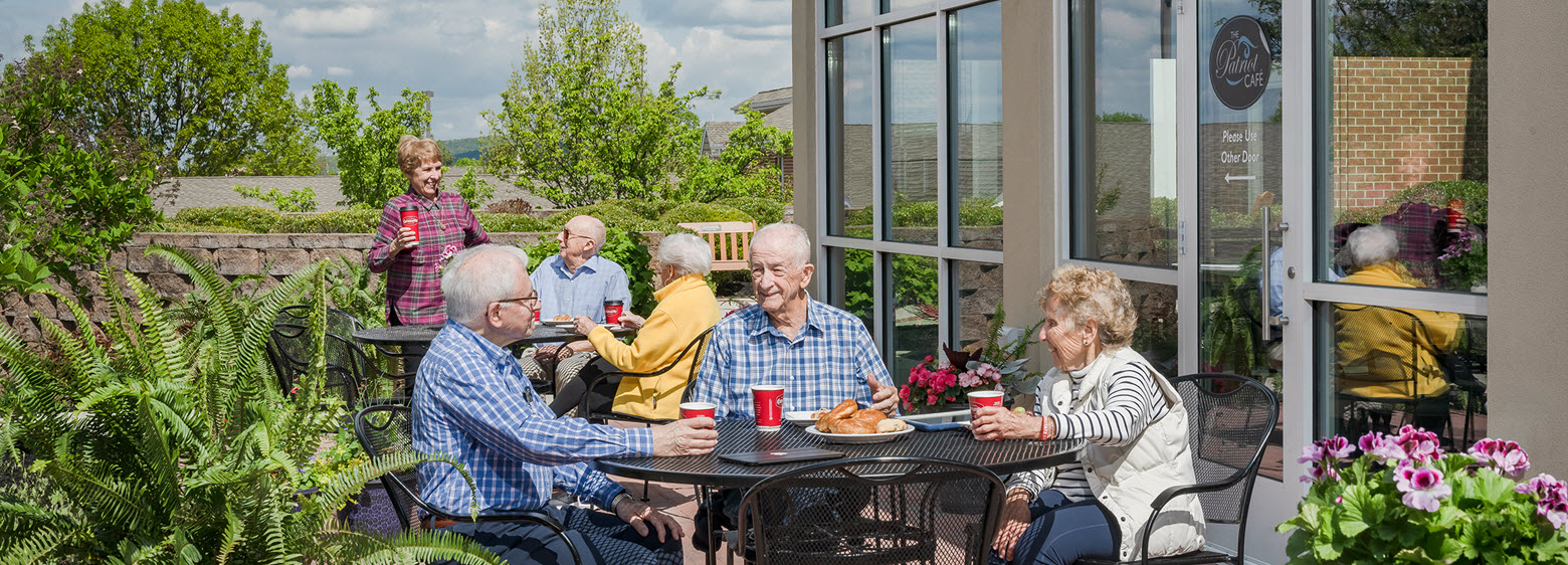 two tables of seniors on patio outside of patriot cafe enjoying breakfast and conversation