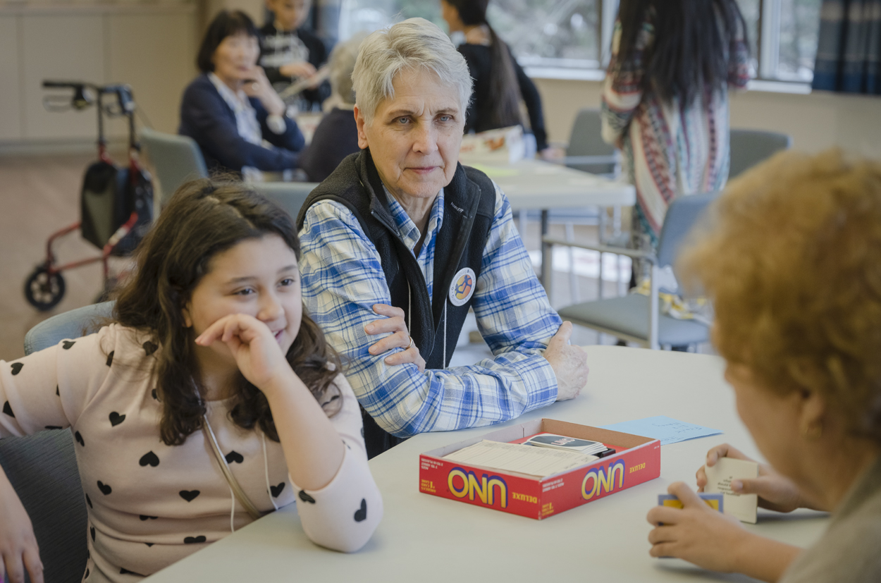 older woman with middle aged school girl playing board games together