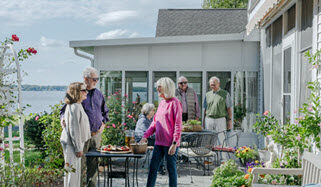 group of seniors having ice tea and dessert on their cottage patio with river in the background