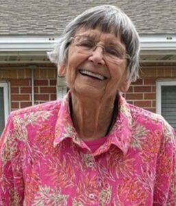 photo of older woman in pink shirt smiling outside