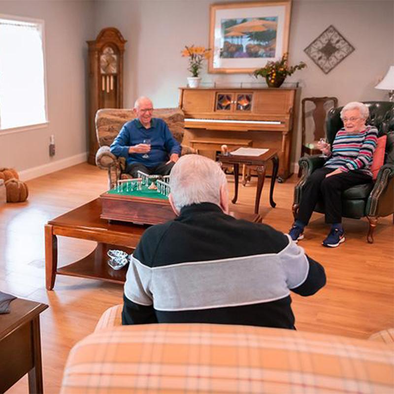 three seniors sitting in common area talking and drinking wine