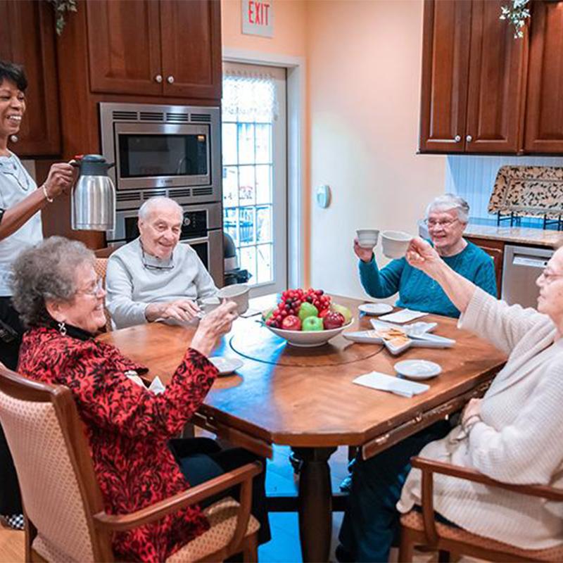 group of five seniors in someones apartment having coffee