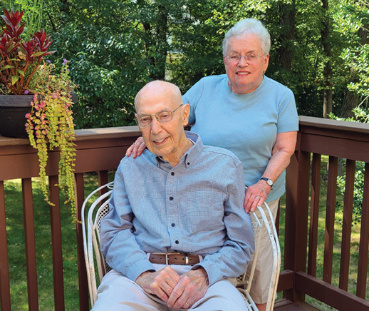 senior man sitting in chair with senior woman behind him